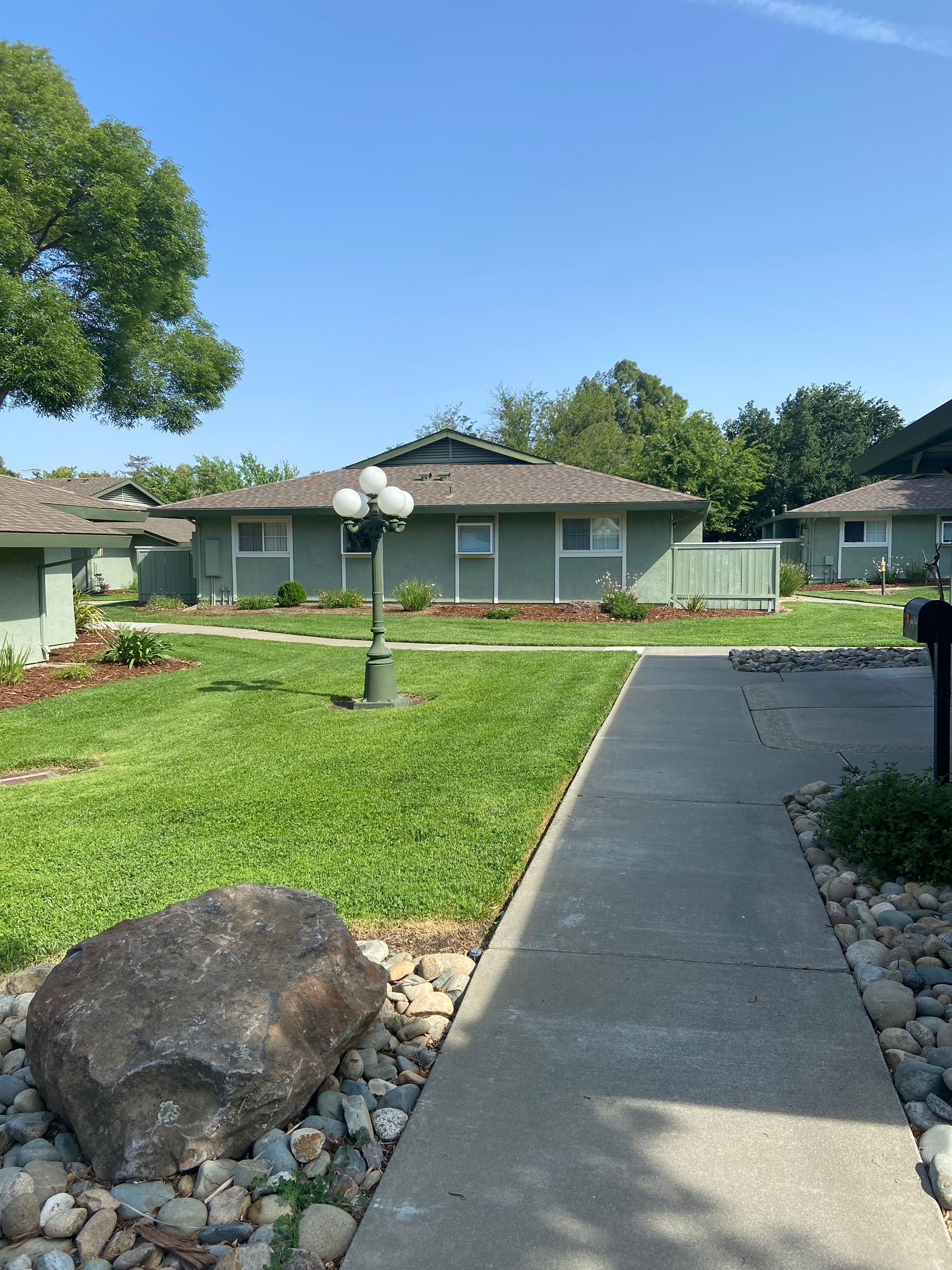 A walkway leading to a house with a large rock in the foreground