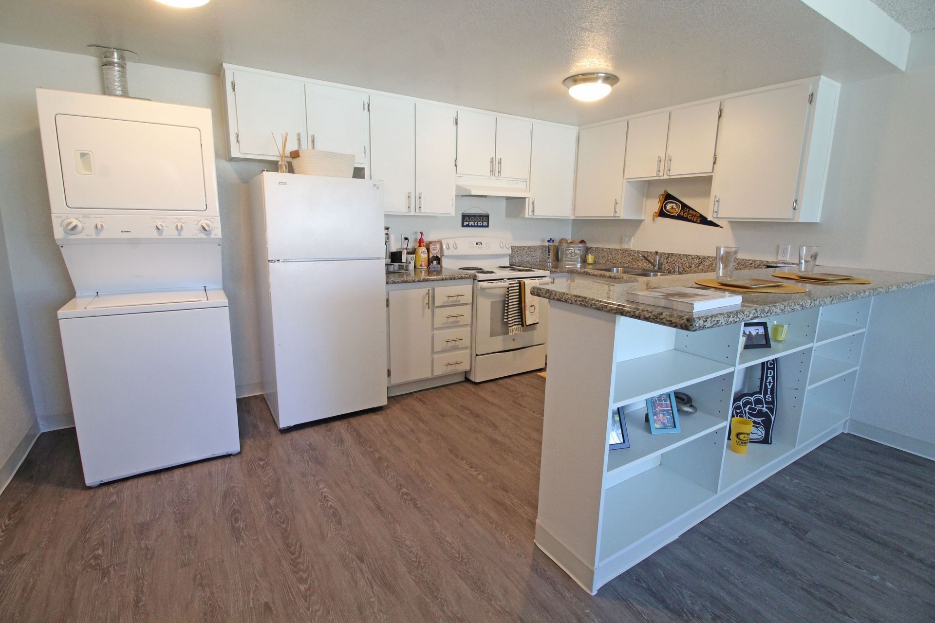 A kitchen with white cabinets , a refrigerator and a washer and dryer.