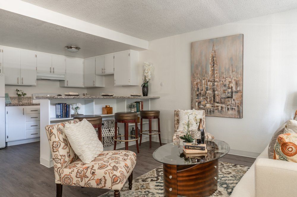 A living room with a couch , chair , coffee table and a painting on the wall.
