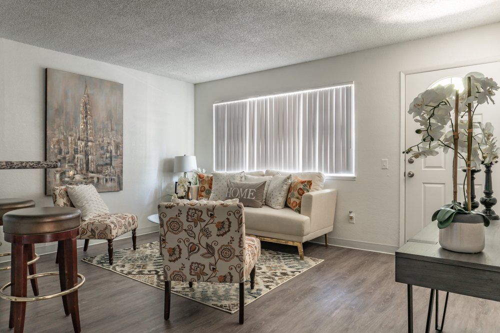 A living room with a couch , chairs , a table and a window.