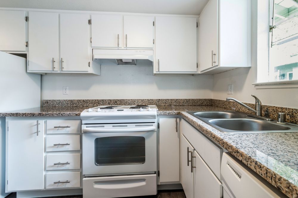A kitchen with white cabinets and granite counter tops