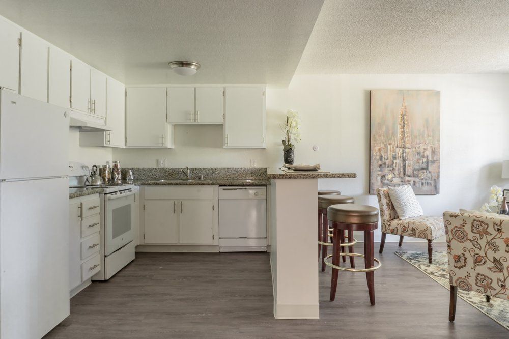 A kitchen with white cabinets , a refrigerator , a stove , and a bar.