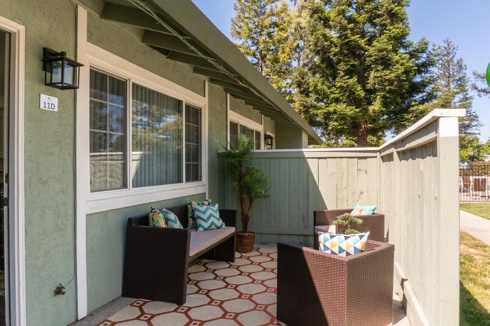 A patio with a bench and chairs in front of a house.