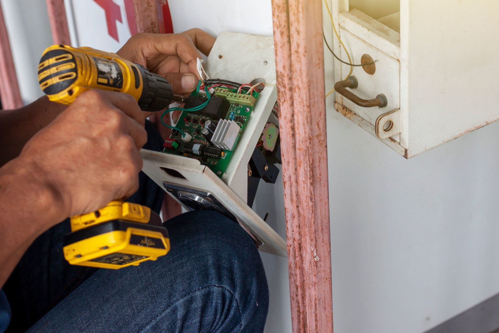 A man is using a drill to fix a door.