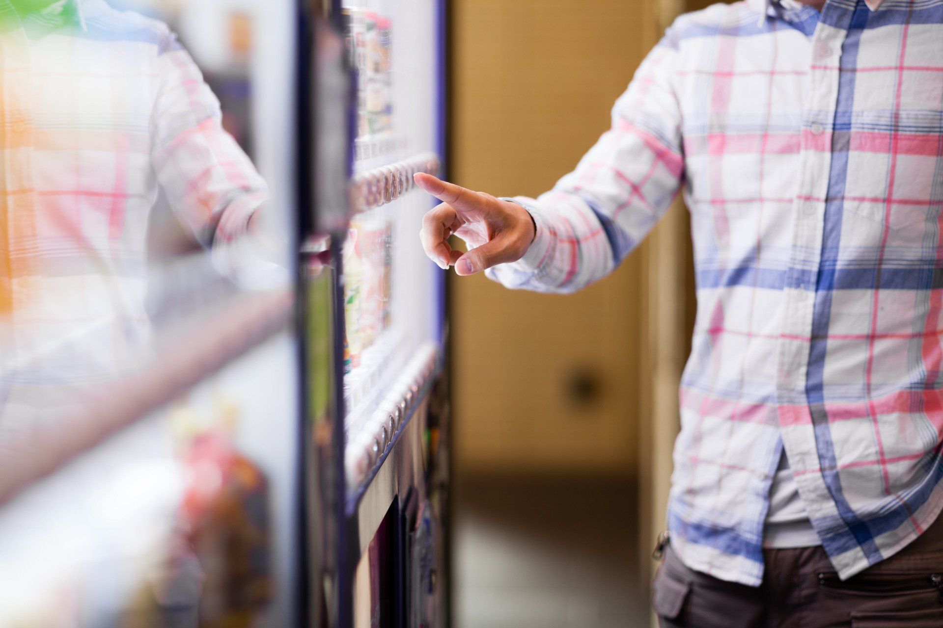 A man in a plaid shirt is using a vending machine.