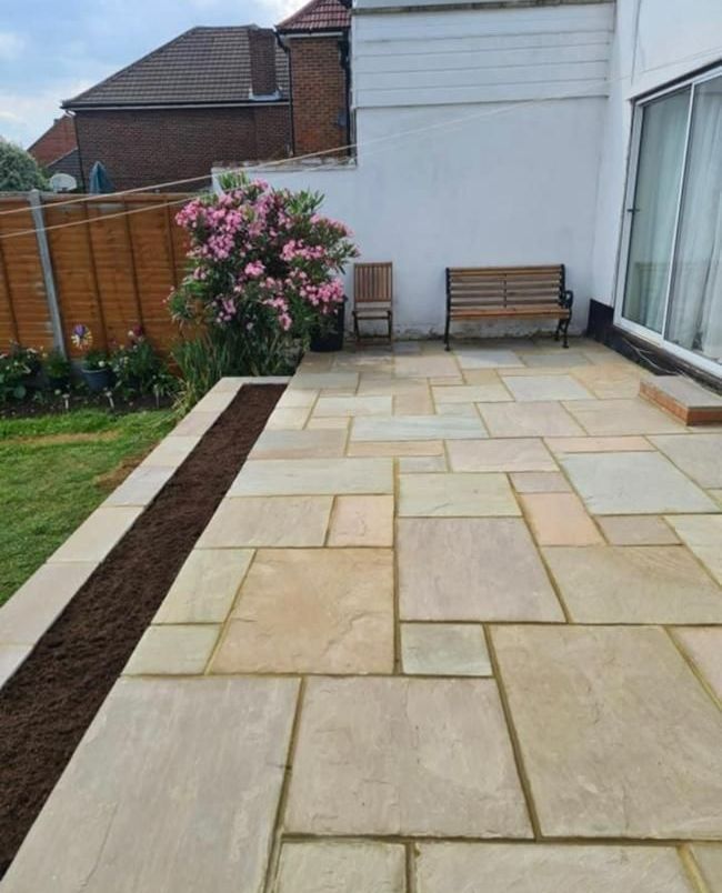 A patio with a bench and chairs in the backyard of a house