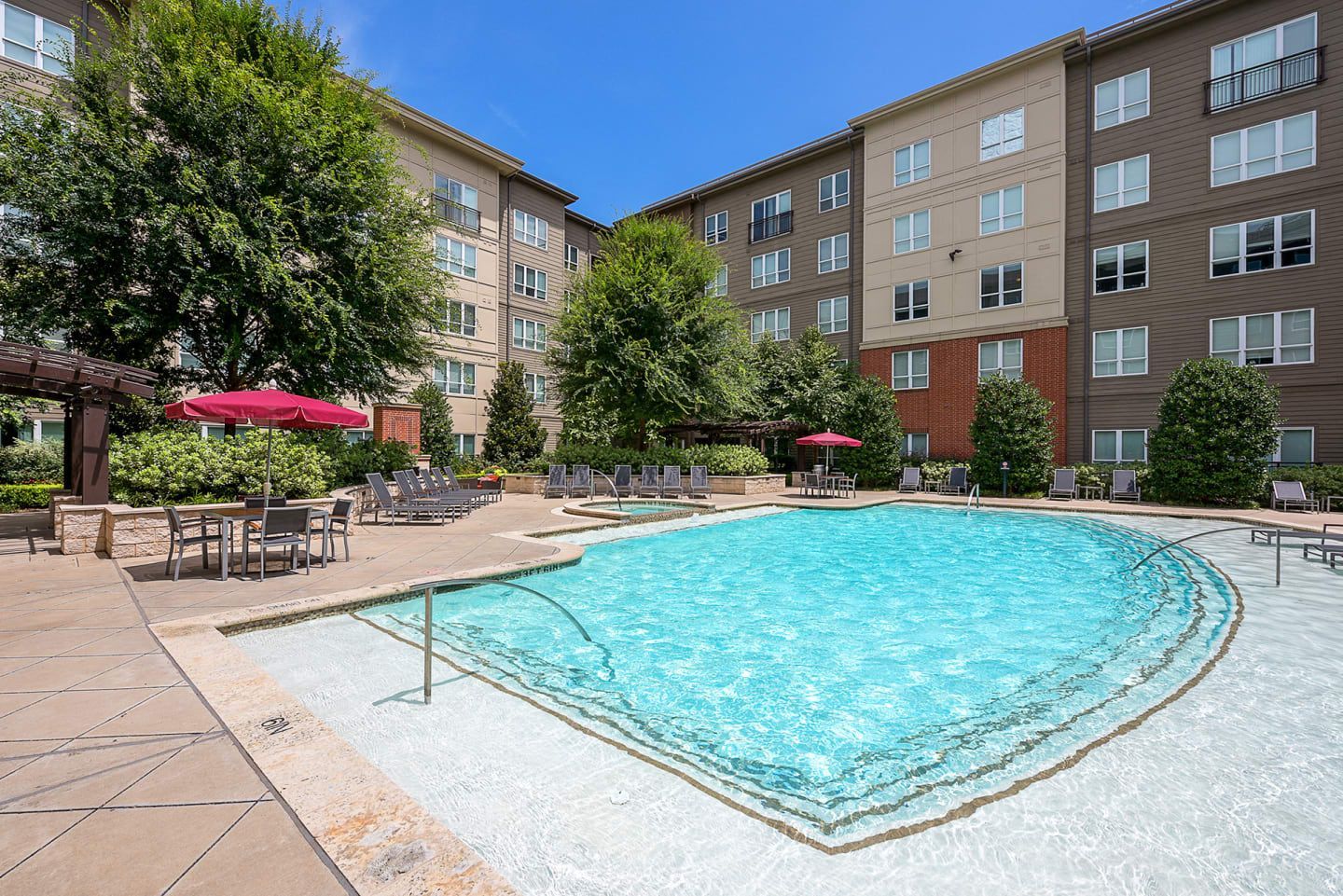 A large swimming pool in front of a large apartment building.