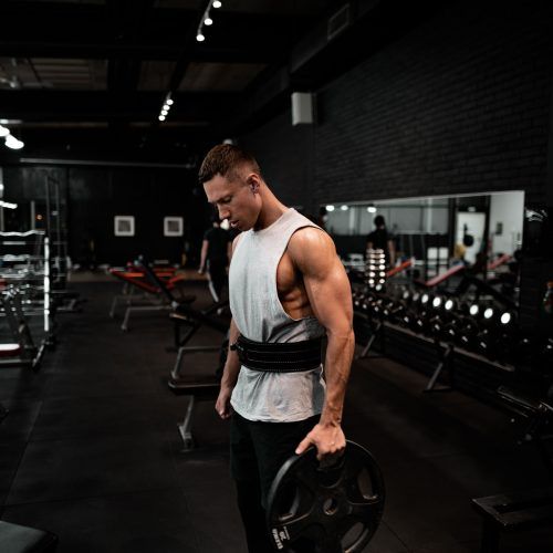 A man is holding a barbell in a gym.