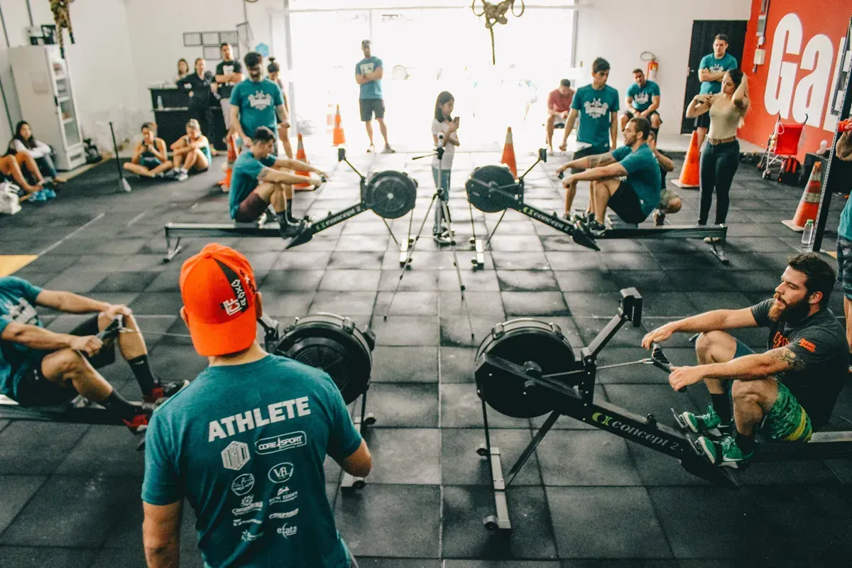 A group of people are sitting on rowing machines in a gym.