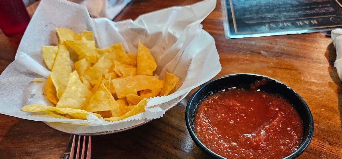 Basket of tortilla chips with salsa on a wooden table