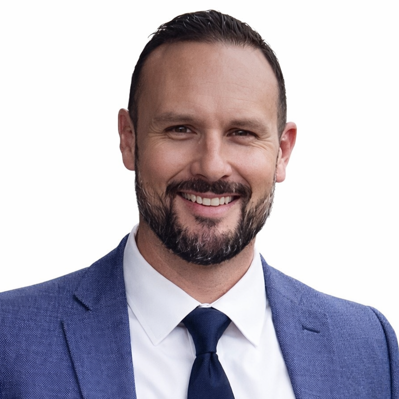 Man in blue suit smiles, headshot.