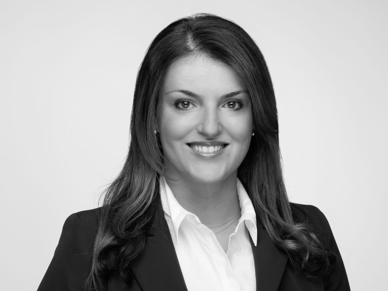 Woman in professional attire, smiling. Black and white headshot.