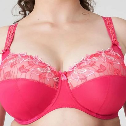 Donna che indossa un reggiseno rosa acceso con dettagli in pizzo floreale sulle coppe.