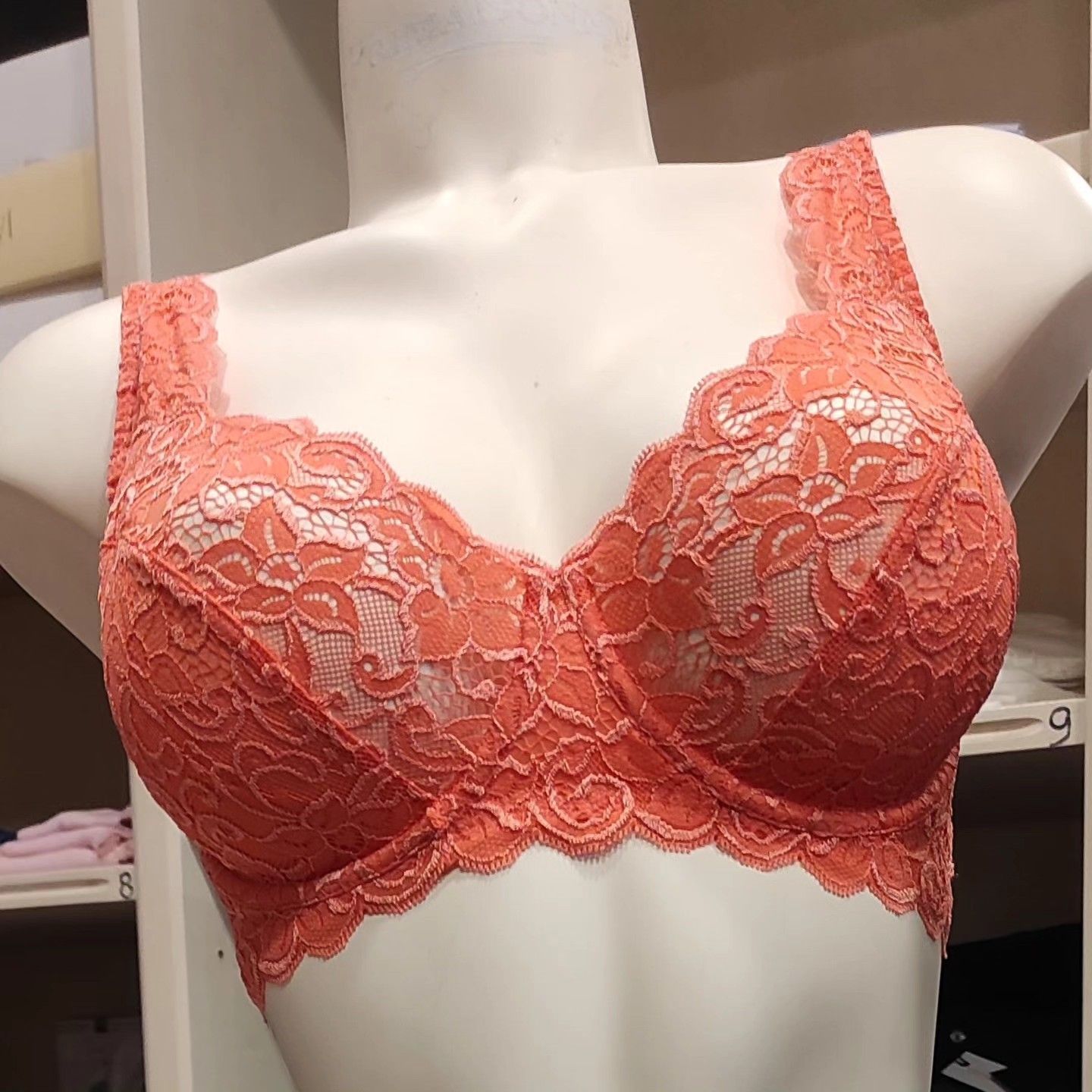 Reggiseno in pizzo corallo esposto su un manichino.