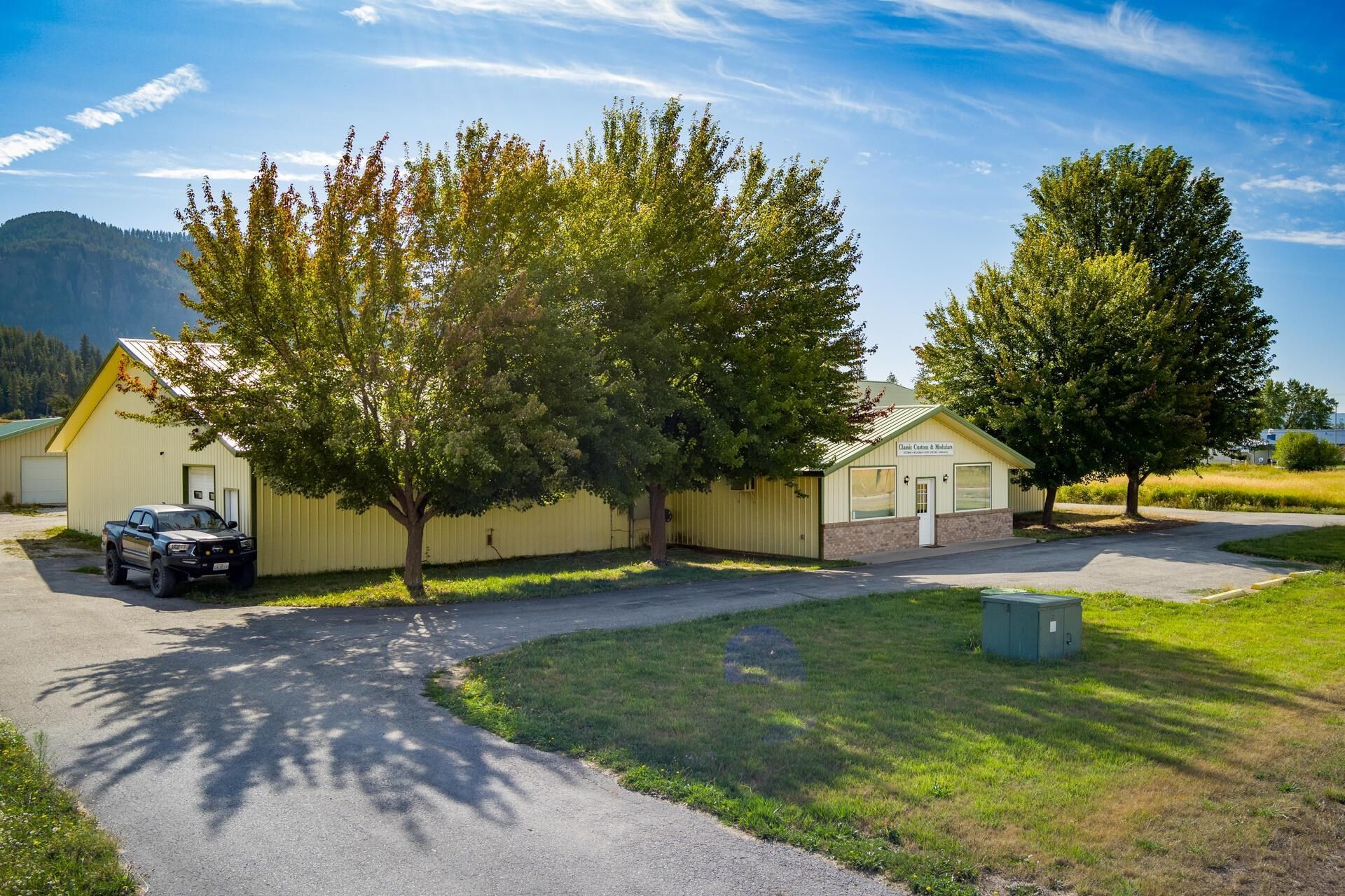 Suburban houses with trees, a parked car, and a grassy yard under a blue sky