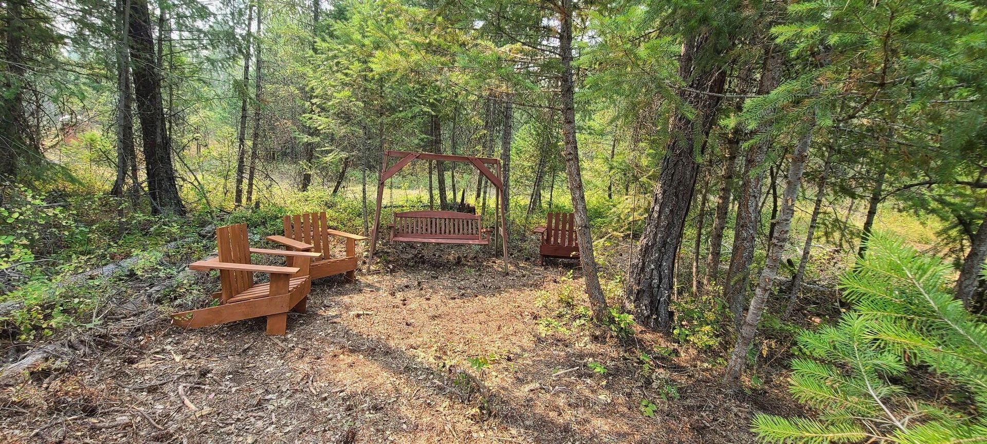 Wooded picnic area with orange benches and a fire pit among trees and fallen leaves