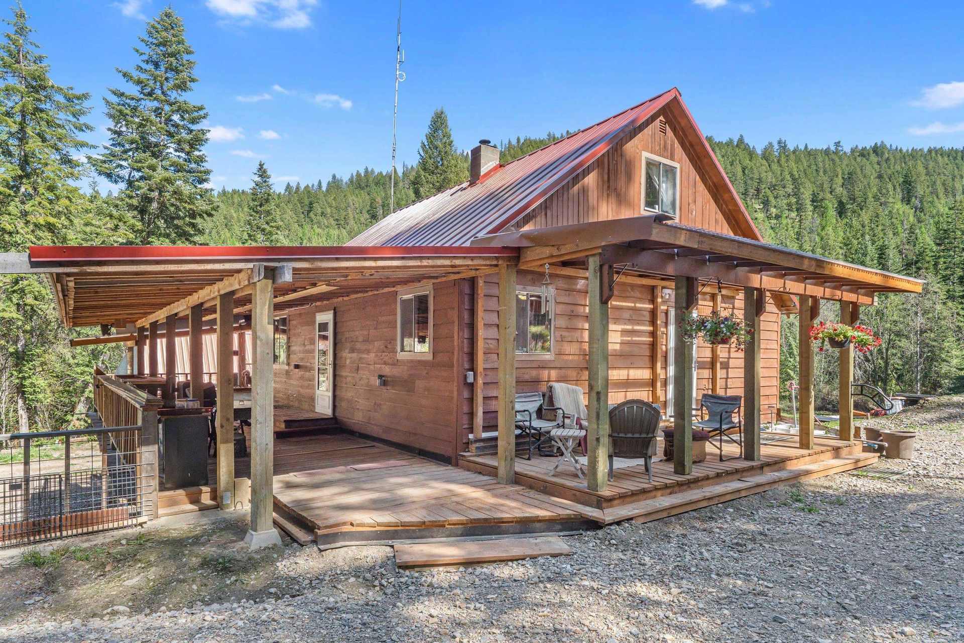 Rustic cabin with covered porch and large windows in a wooded mountain setting