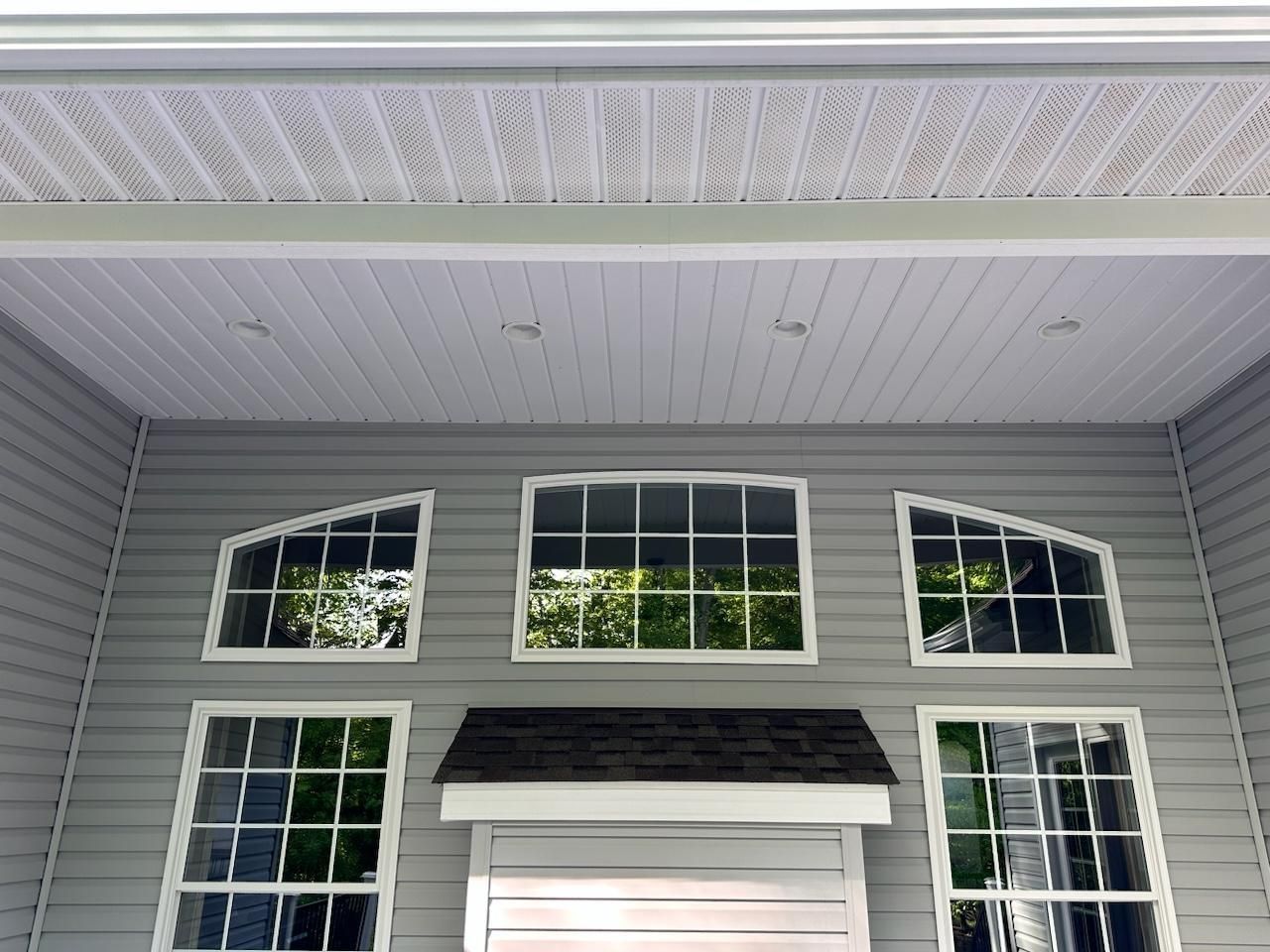 Gray house exterior with windows, roof, and white trim.