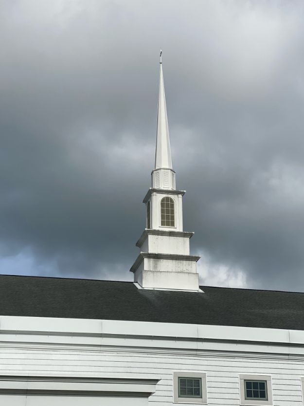 White church steeple against a dark, cloudy sky.