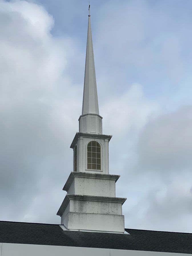 White church steeple against a cloudy sky.