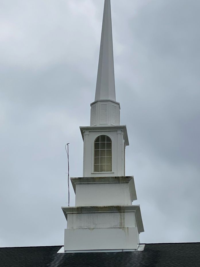 White church steeple against a cloudy sky.