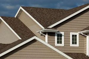 Brown roofed house with white trim, tan siding, and two windows.