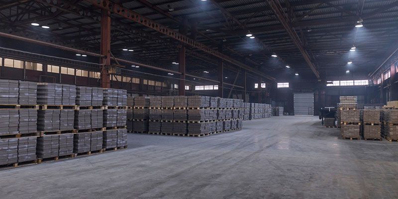 Interior of a large warehouse with stacks of boxes, lit by overhead lights.