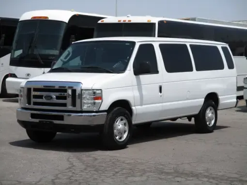 Dark blue sedan parked on a concrete surface, with a chain link fence and buildings in the background.