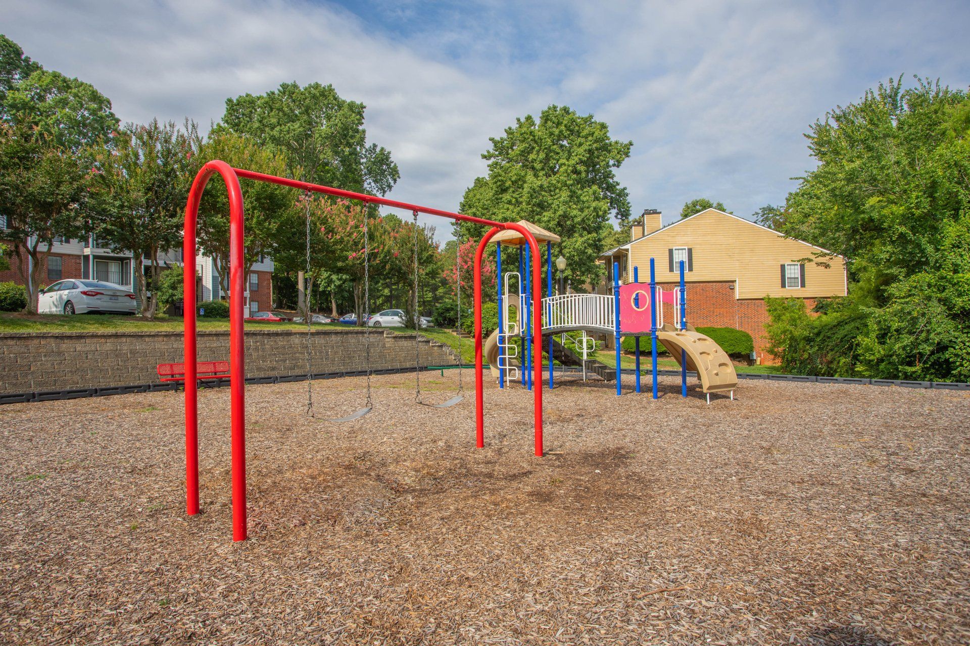A playground with a red swing set and a blue slide at Autumn Ridge.
