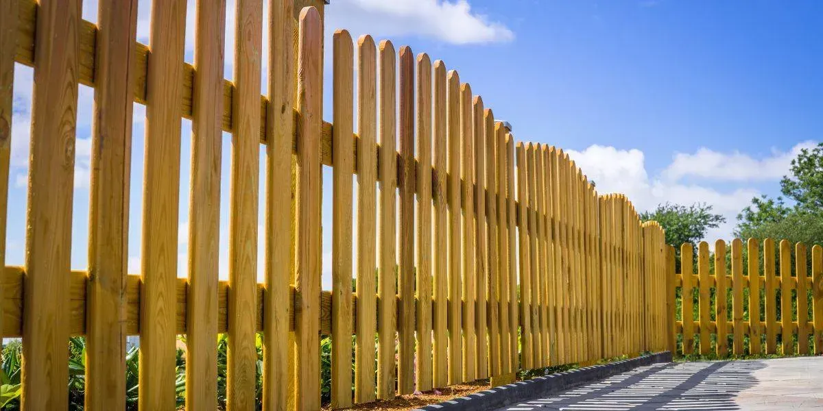 Wooden fence against a blue sky with clouds.