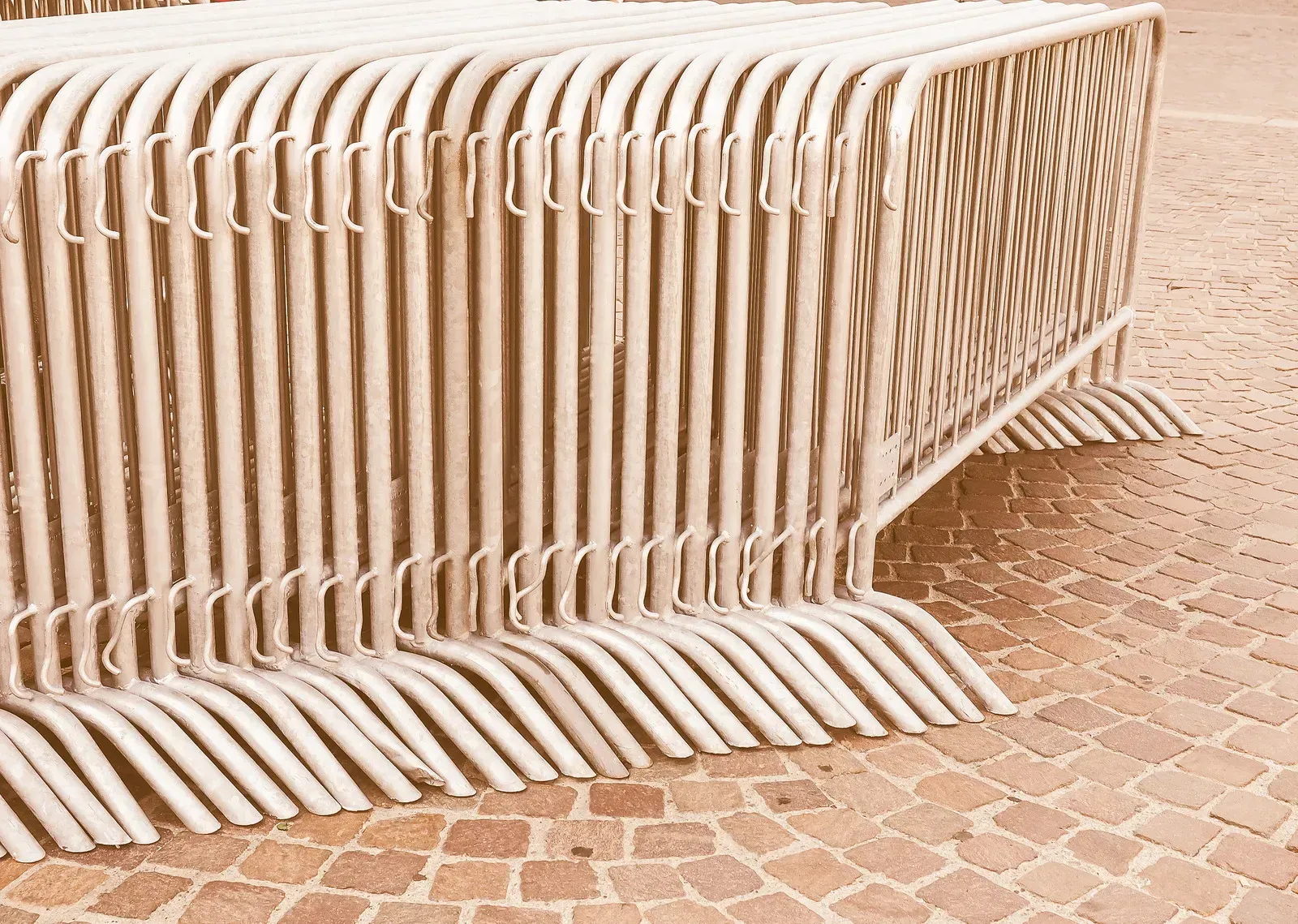 Stacked metal crowd control barriers on a cobblestone surface.