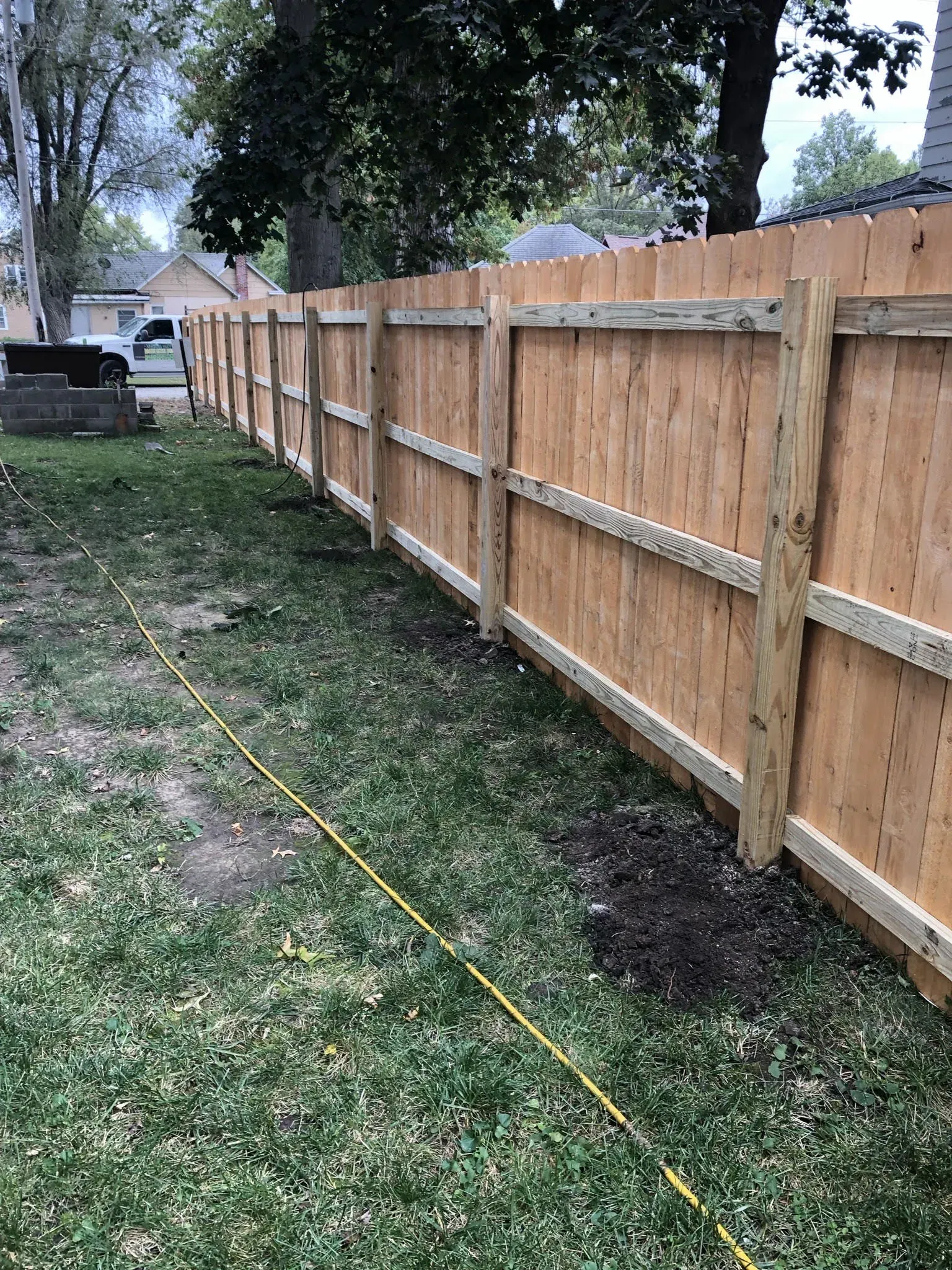 Wooden fence in a yard with grass and a guide string.