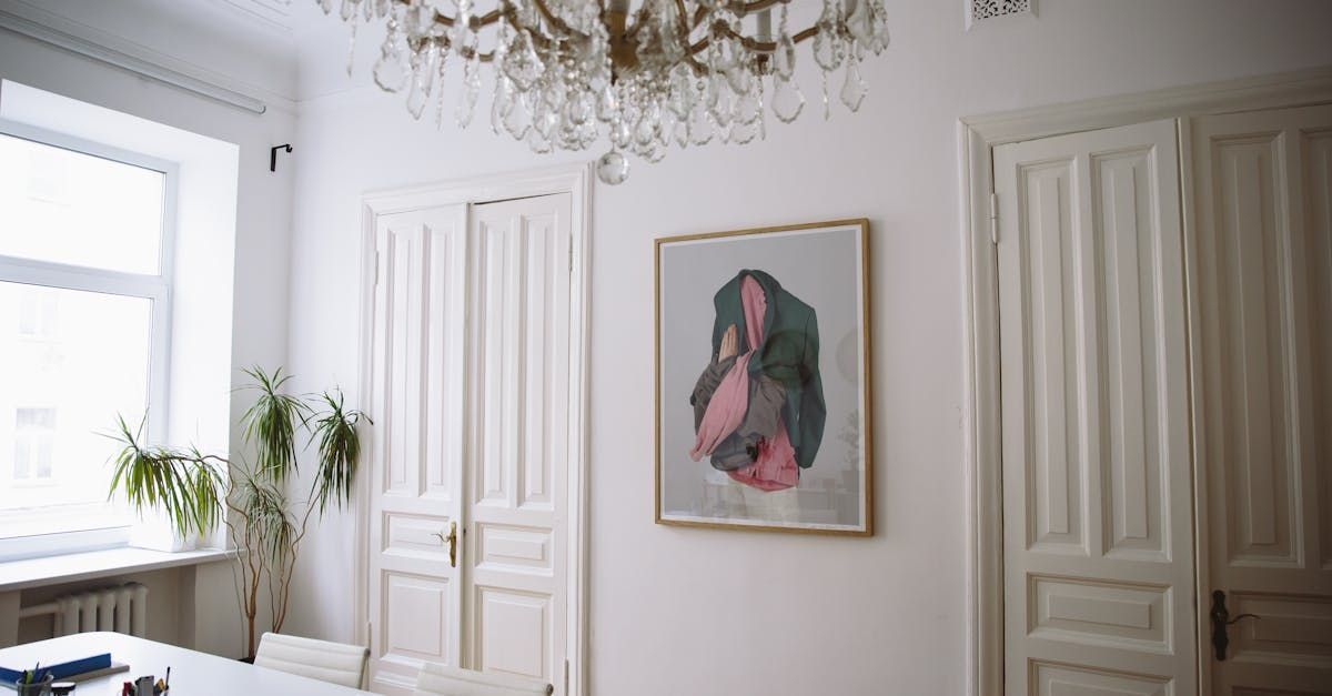 A dining room with a table , chairs , a chandelier and a painting on the wall.