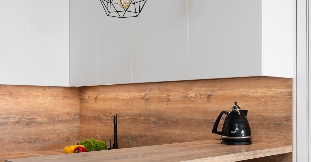 A kitchen with a wooden counter top and a black kettle on it.