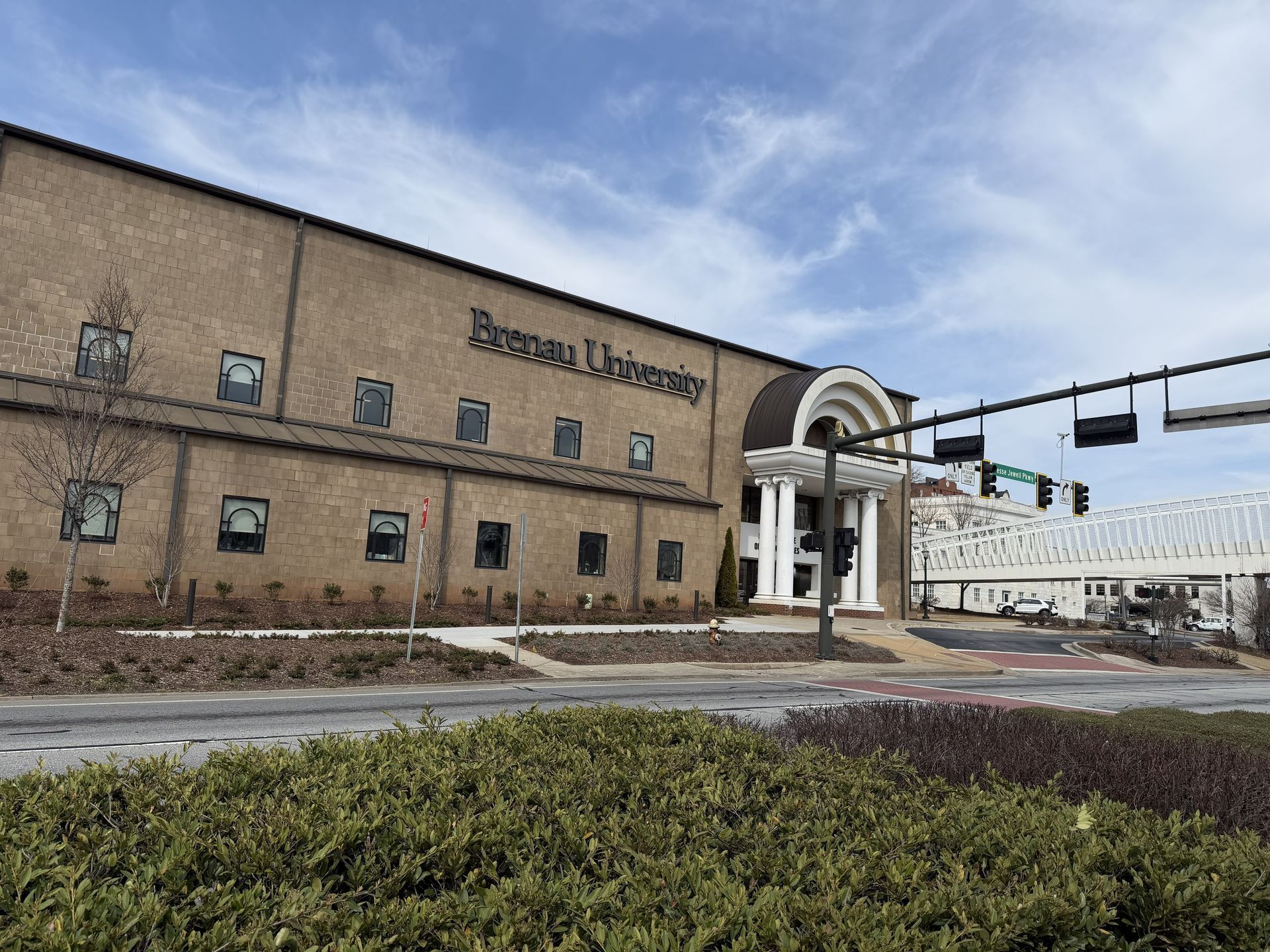 Exterior view of Brenau University building with a walkway over a street under a partly cloudy sky.