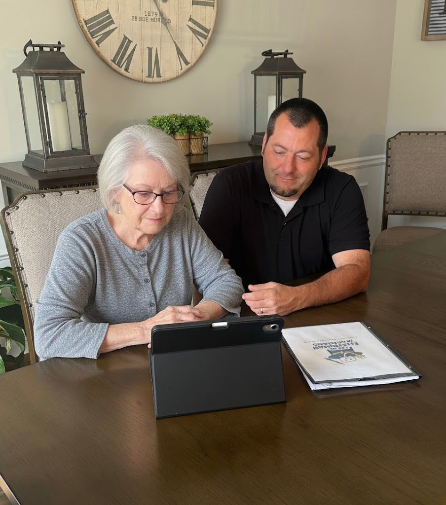 Woman and man looking at a tablet together at a table. A book lies open next to the tablet.