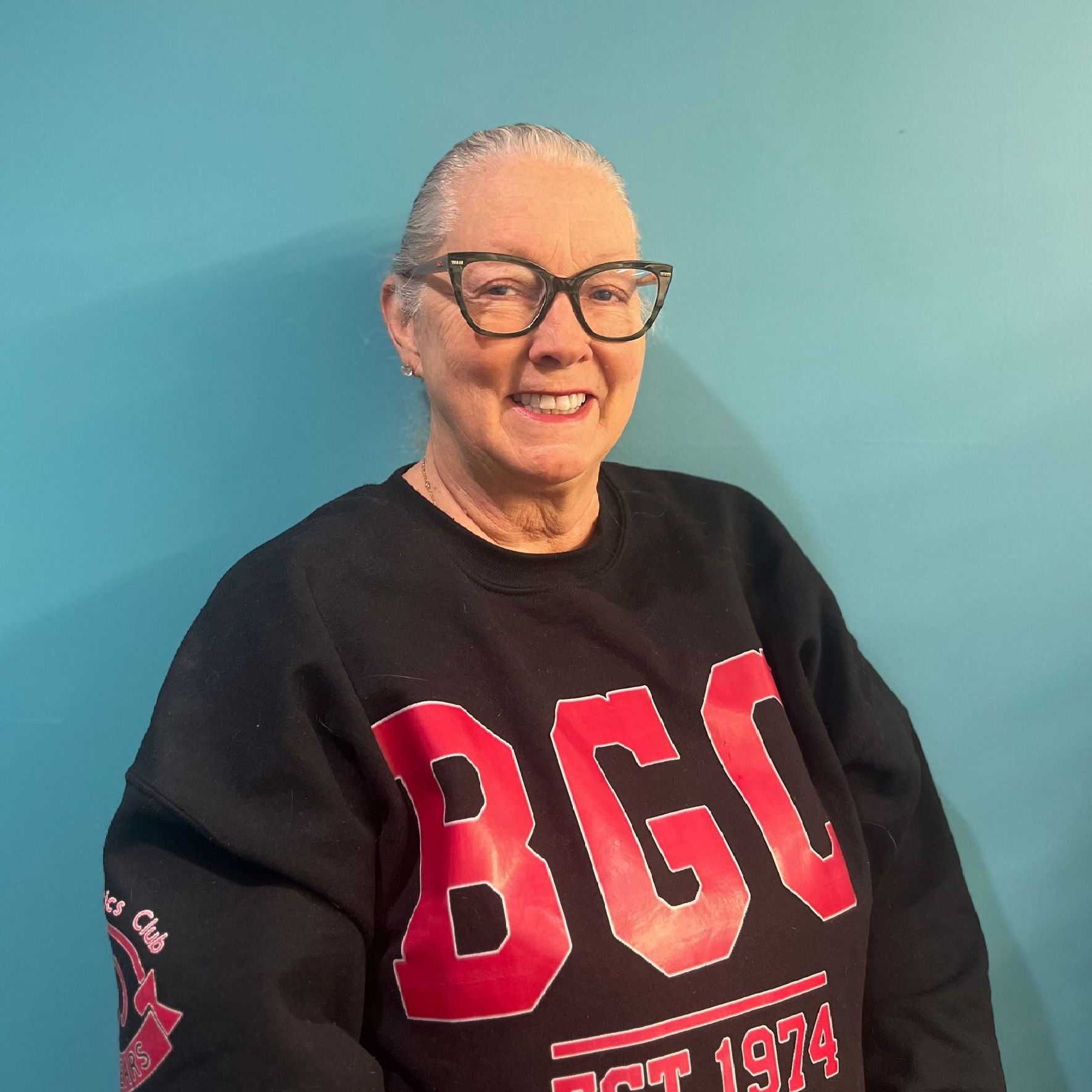 A woman wearing glasses and a black sweater that says bgi