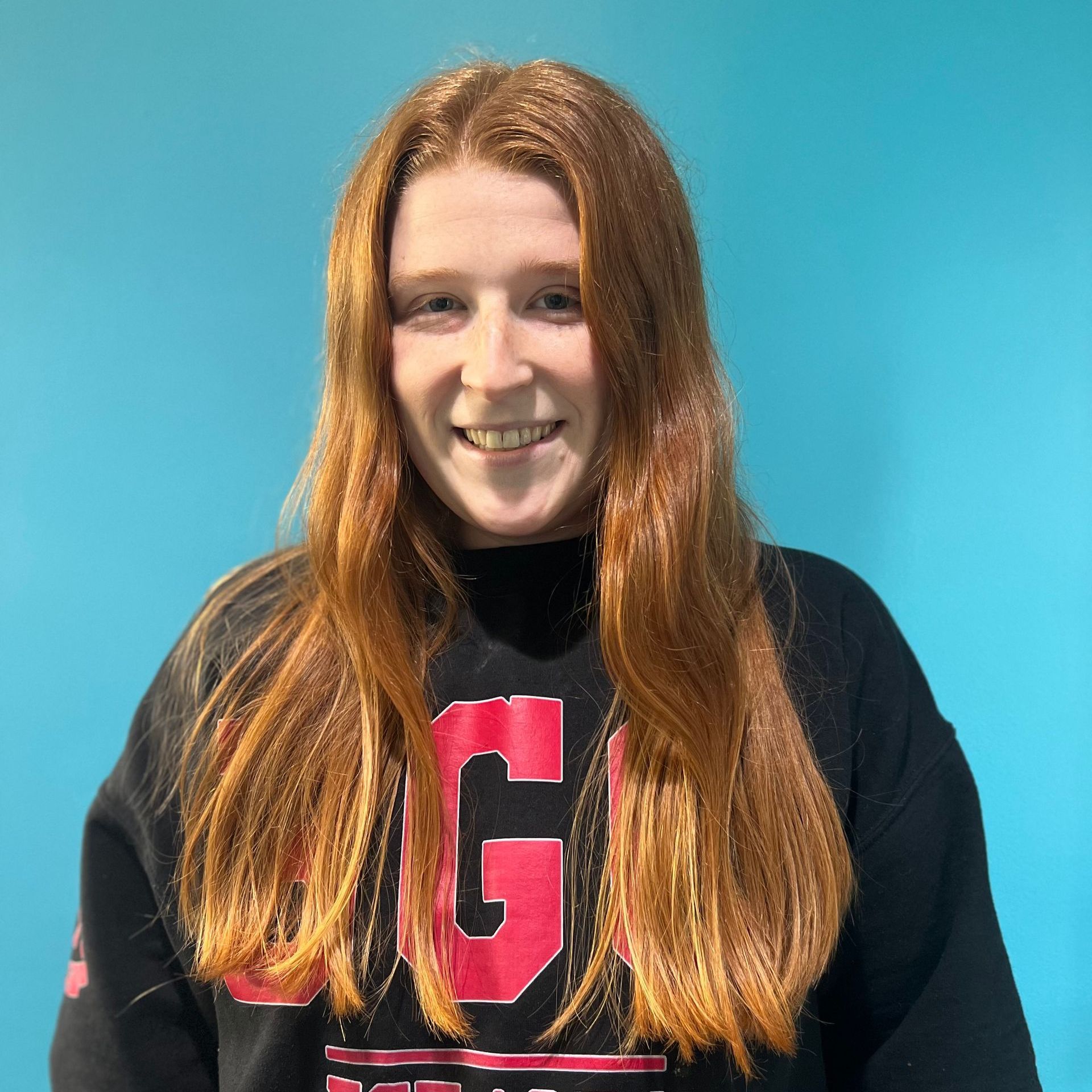 A woman wearing a black sweater with the letter g on it