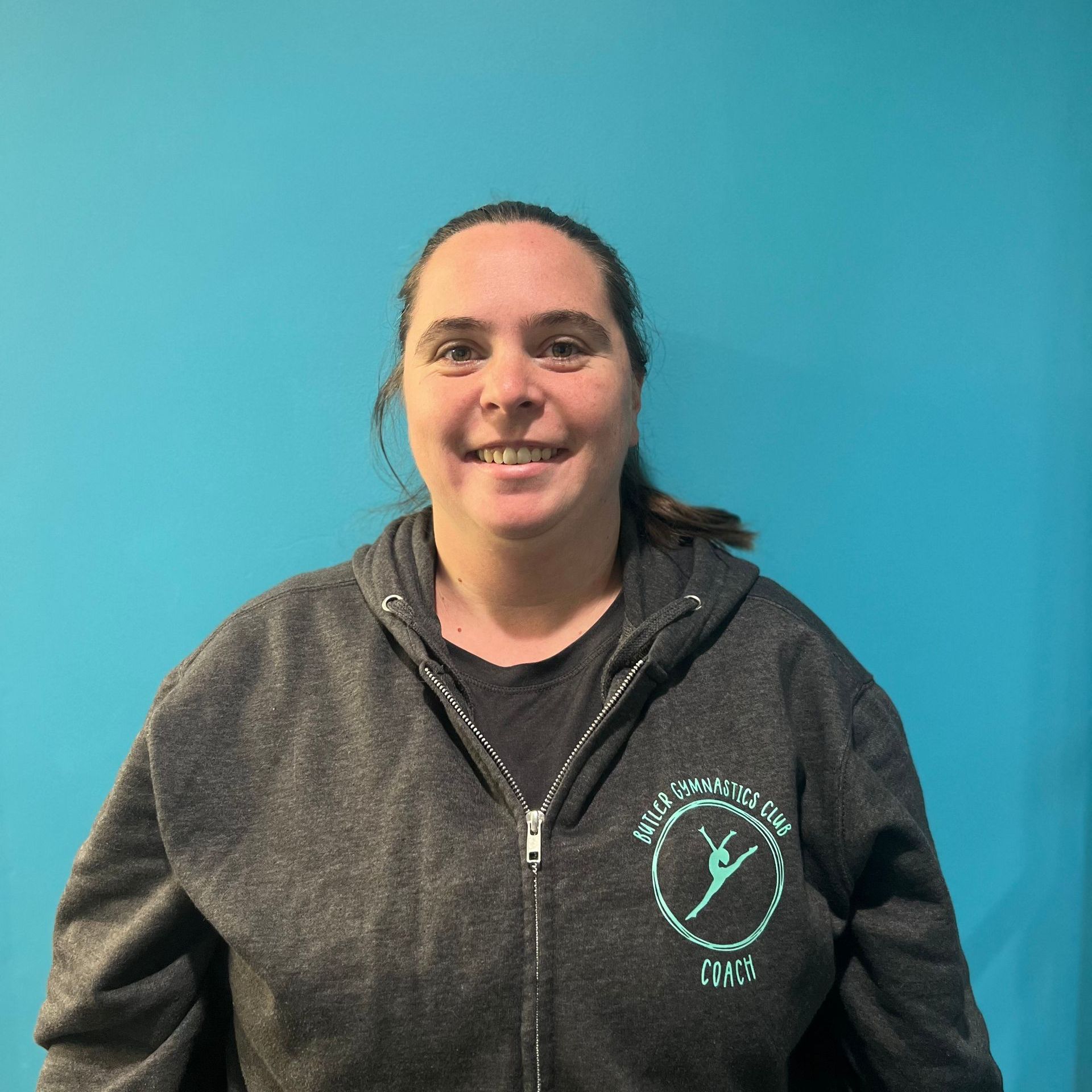 A woman wearing a grey sweatshirt with a logo on it