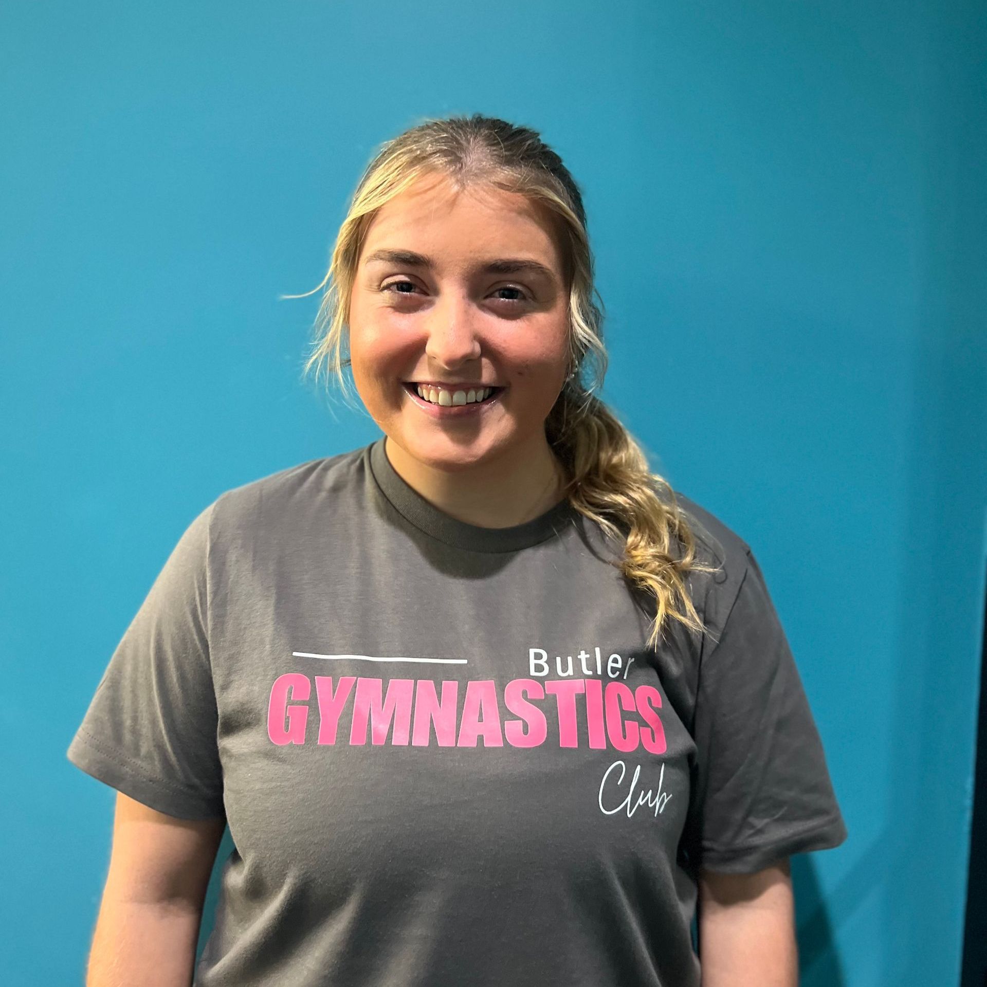 A woman wearing a gray t-shirt with the word gymnastics on it