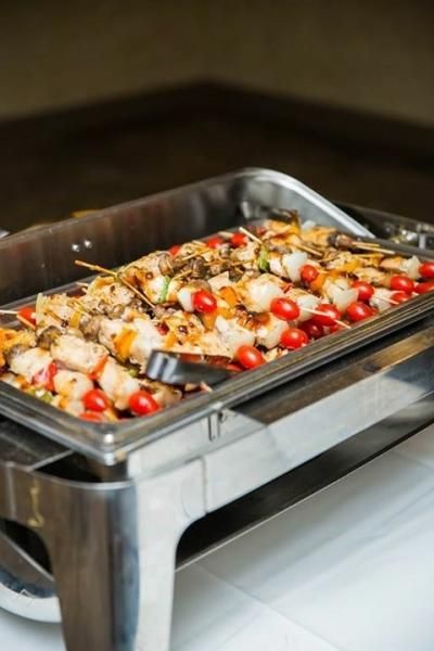A tray of food with tomatoes and shrimp on skewers on a table.