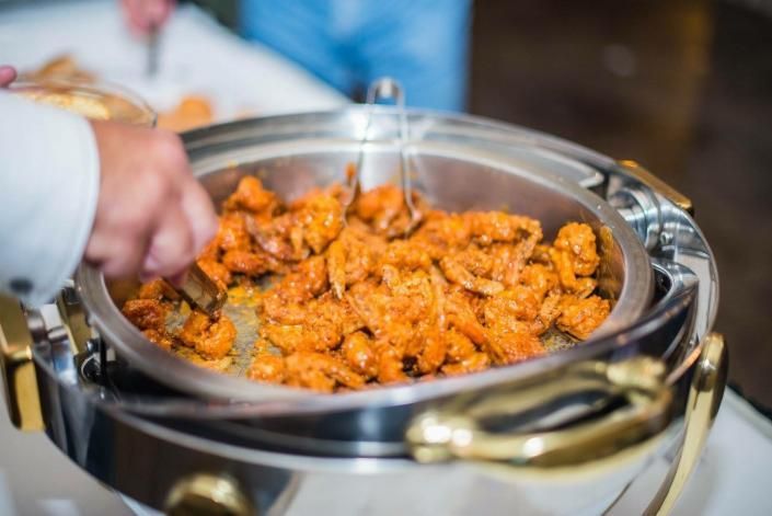 A person is taking a bowl of shrimp from a buffet.