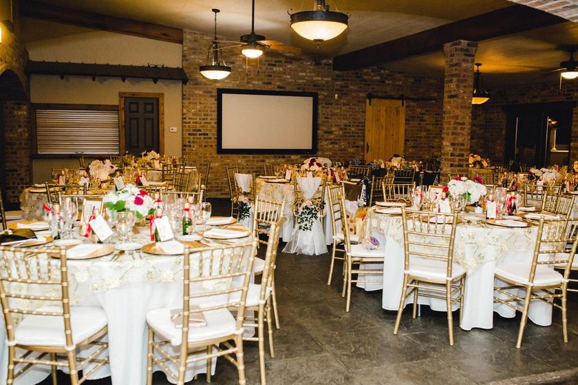 A large room with tables and chairs set up for a wedding reception.