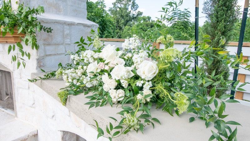 A large bouquet of white flowers and greenery is sitting on a table.