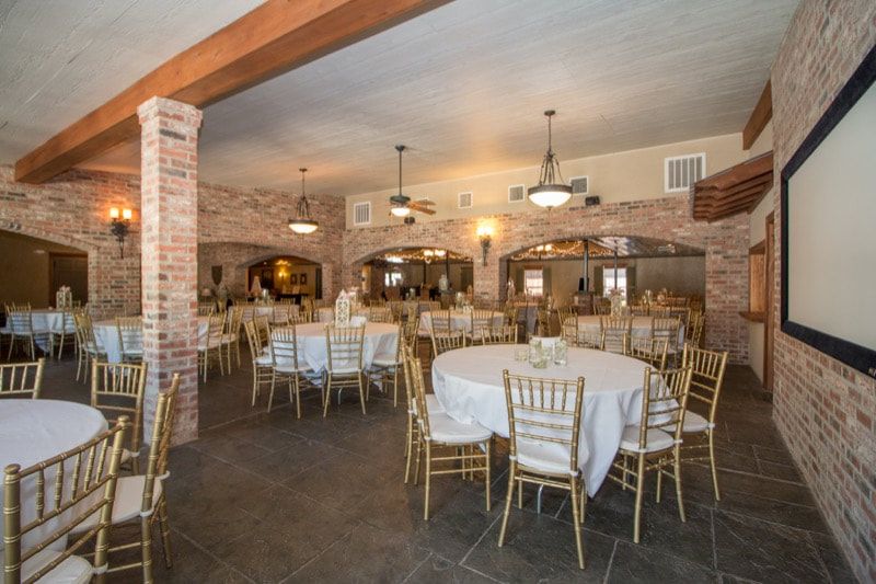 A large room with tables and chairs and a projector screen.