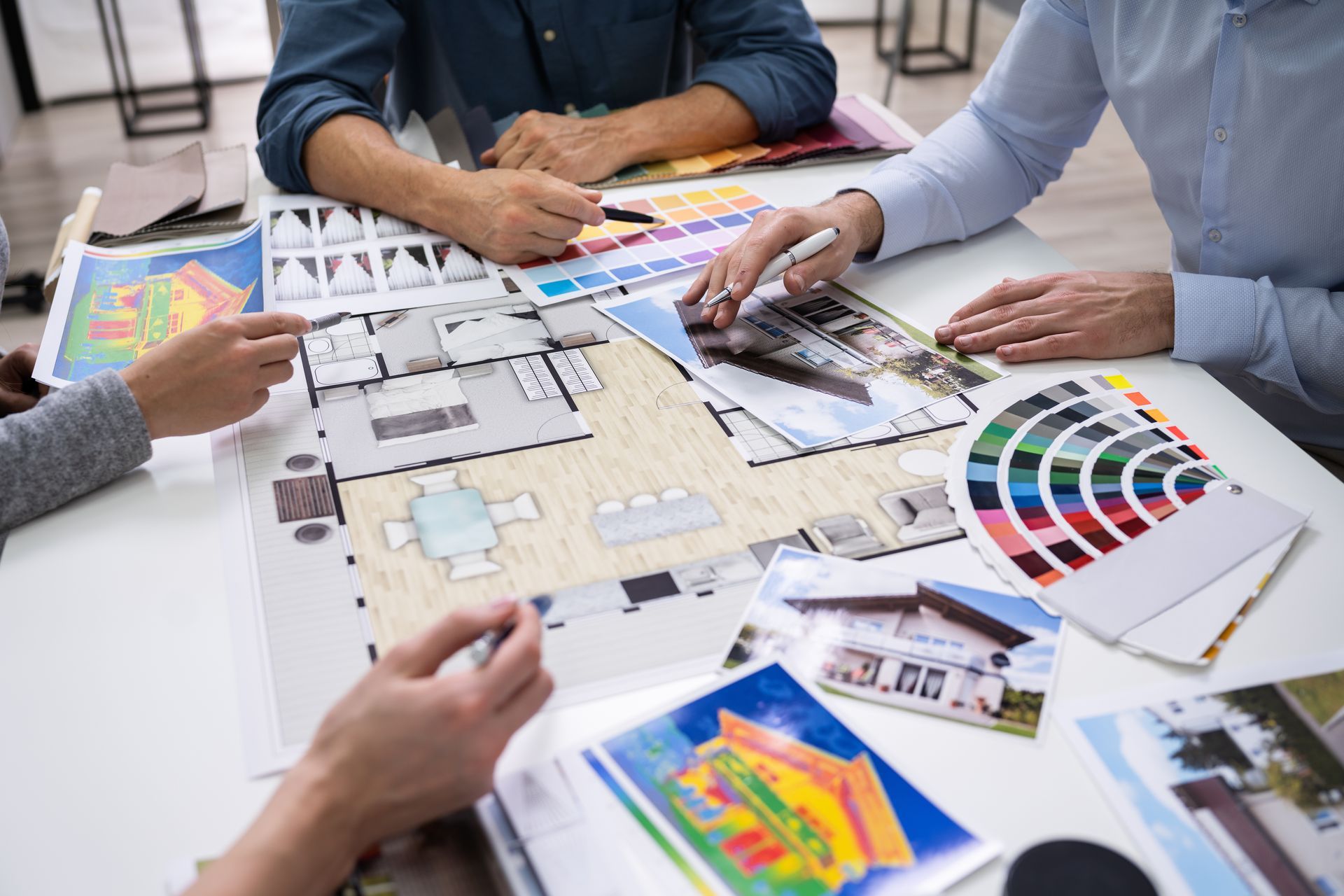 A group of people are sitting around a table looking at a floor plan.