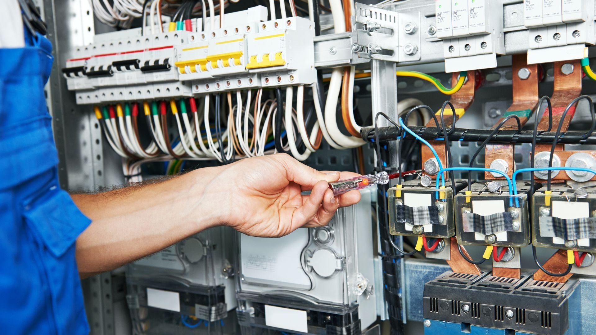 A man is installing an electrical outlet on a wall with a drill.