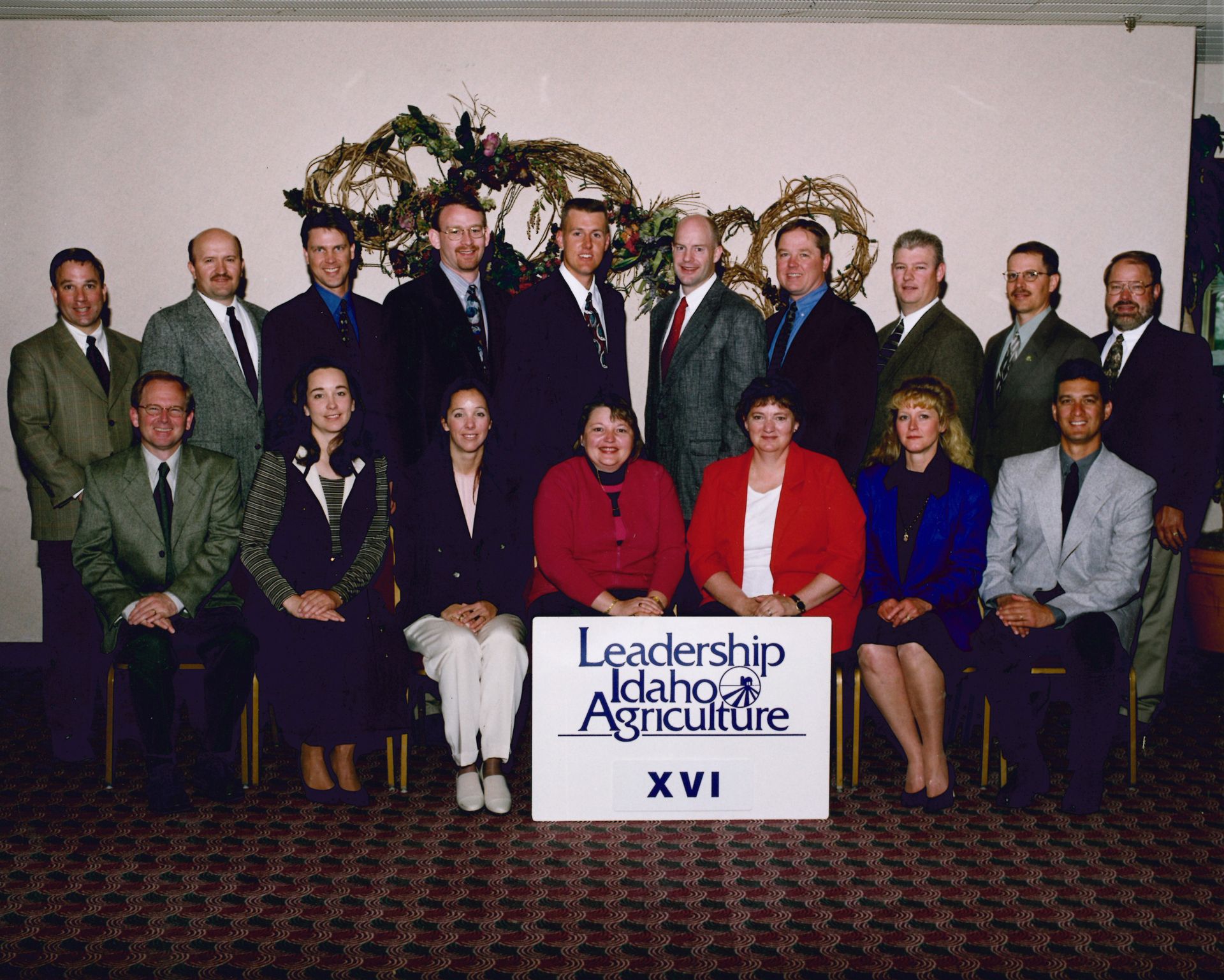 A group portrait of seventeen people posing behind a Leadership Idaho Agriculture XVI sign in an indoor setting.