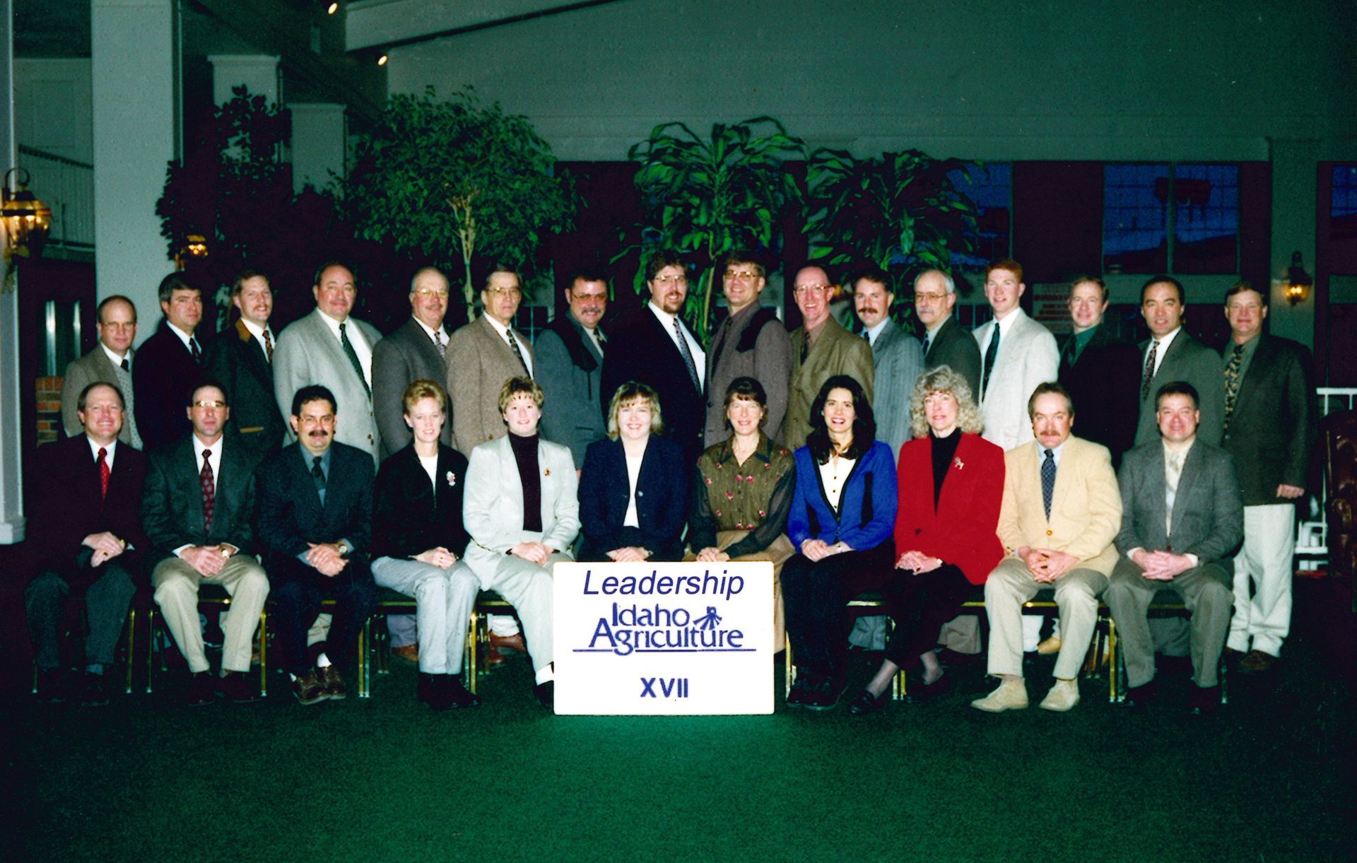 A group of professionals in business attire pose for a formal portrait behind a Leadership Idaho Agriculture XVII sign.