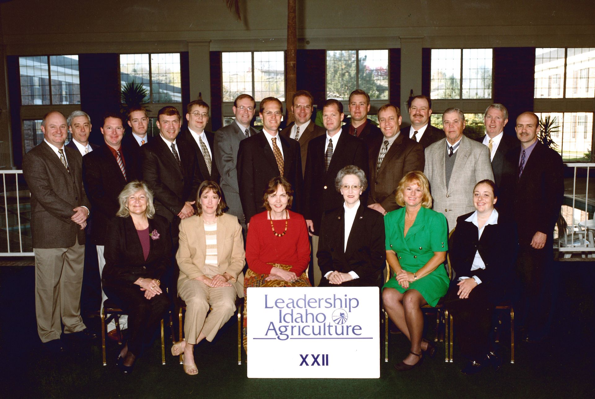 A group of 21 people pose for a formal portrait behind a Leadership Idaho Agriculture XXII sign in an indoor hall.